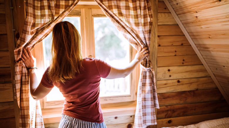 woman opening curtains