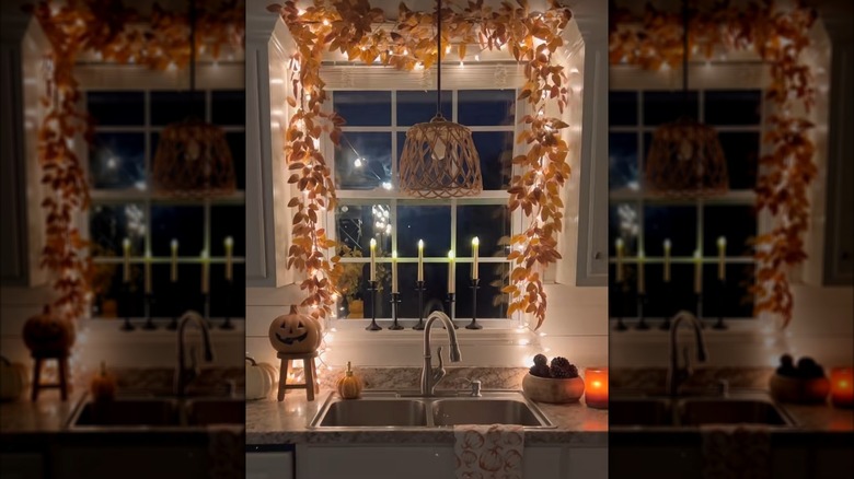 Window decorated for fall with leaf garland and string lights