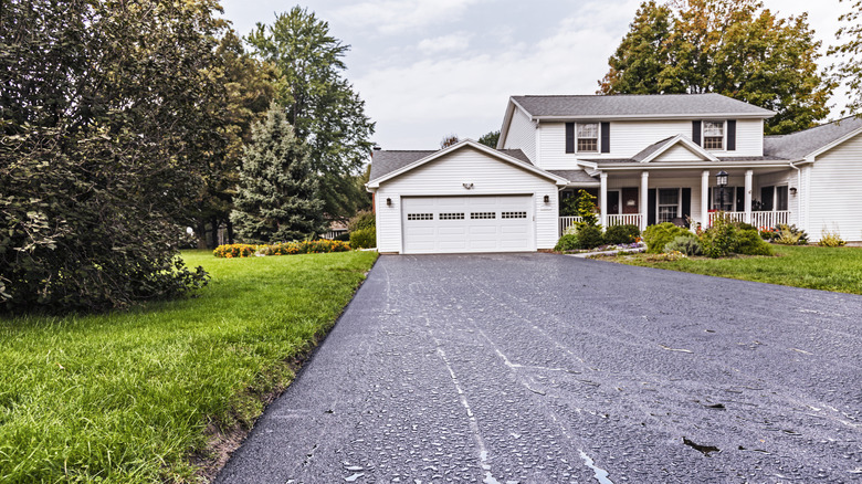 a asphalt driveway with a home in background