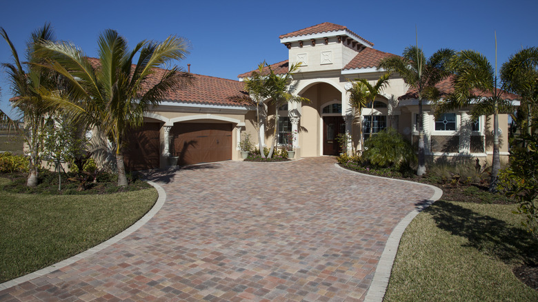a modern home with a brick driveway in front