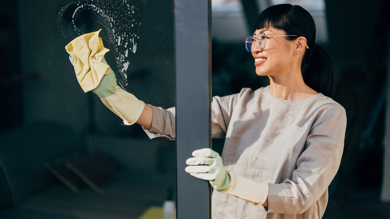 Woman cleaning sliding glass door with soapy microfiber cloth