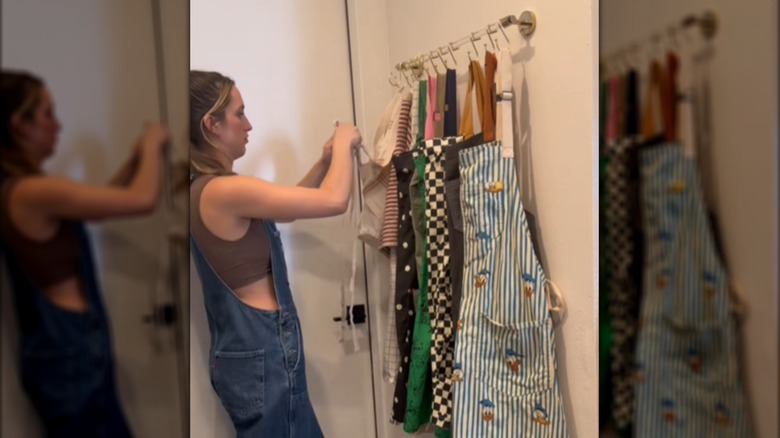 Creator hanging aprons on hooks over a towel bar