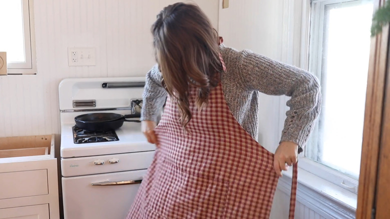 Woman putting on a red plain apron