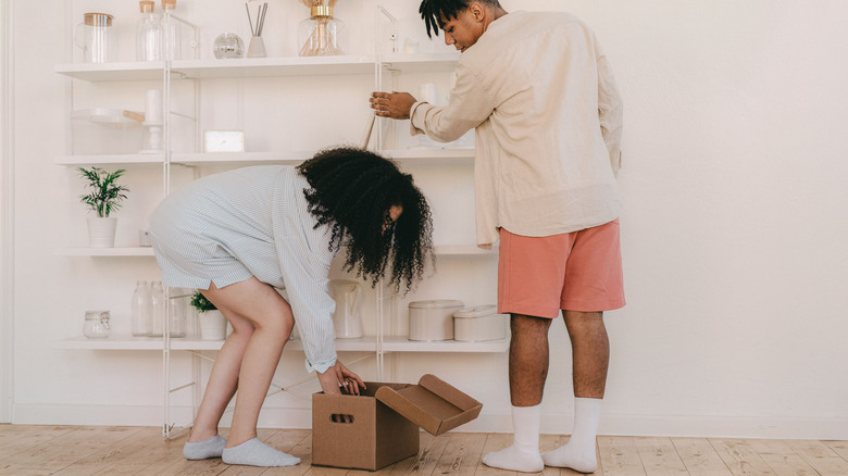 A couple setting up a shelf in their home.