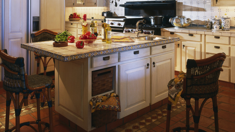 A cluttered kitchen island in a spanish-style kitchen