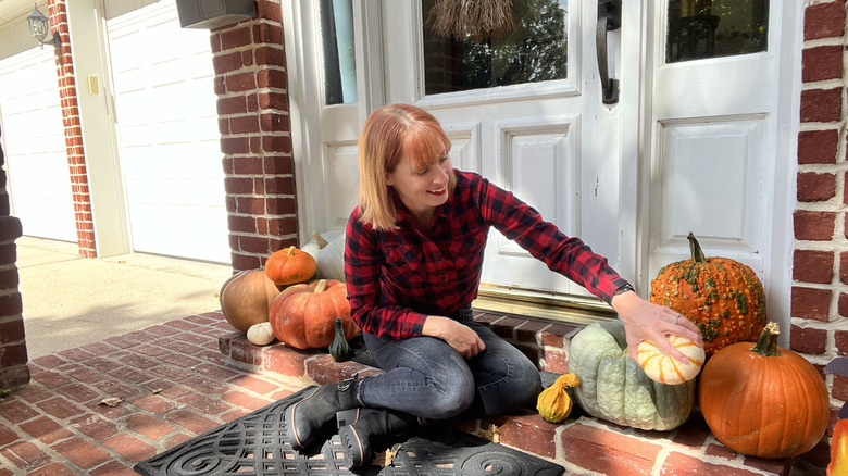Woman decorating her front door for fall with pumpkins
