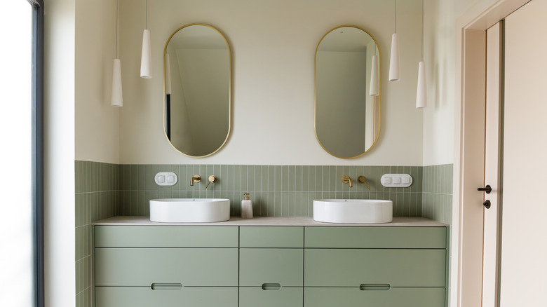 Updated bathroom with two gold-framed oval mirrors