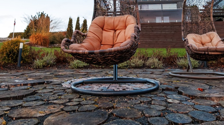 Outdoor lawn charis sitting on a patio made of wood rounds and gravel