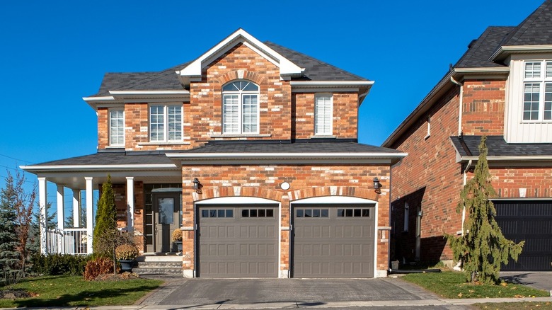 The front of a brick house and empty driveway with paver edging