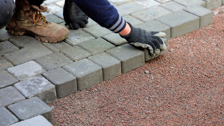 Worker laying down concrete pavers.