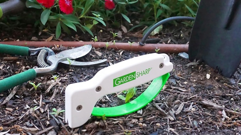 AccuSharp garden tool sharpener against garden tools on the soil