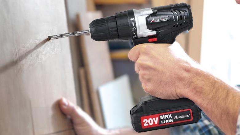 Man using Avid Power 20V Cordless Drill to drill hole in wood plank