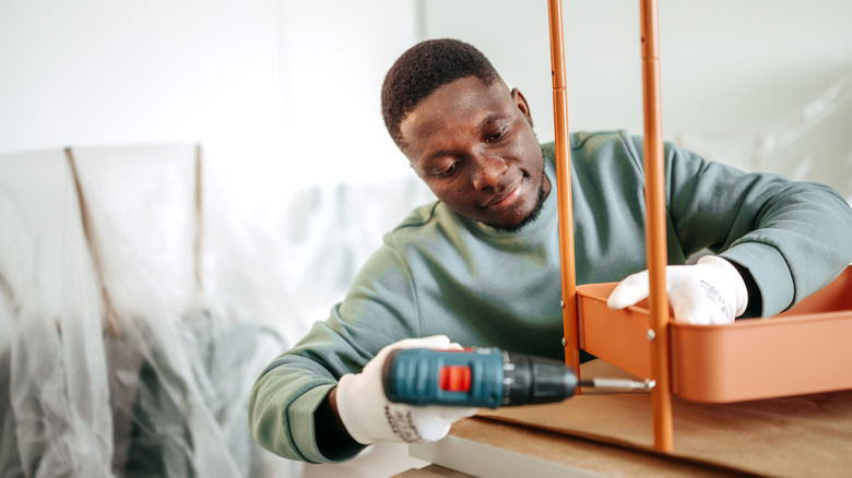 Man assembling furniture with cordless drill