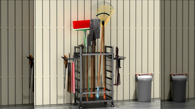 Metal rack for garden tools next to a fence