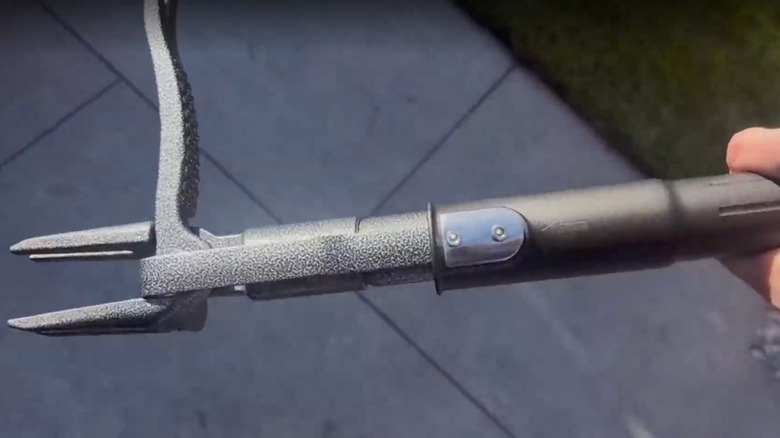 The Bamda weed puller tool held in hand above a driveway