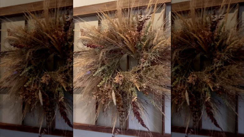 Woman shows how to make a rustic DIY wreath with dry flowers and plants.