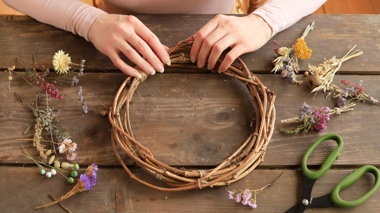 Woman making a rustic DIY wreath with dry flowers and plants.