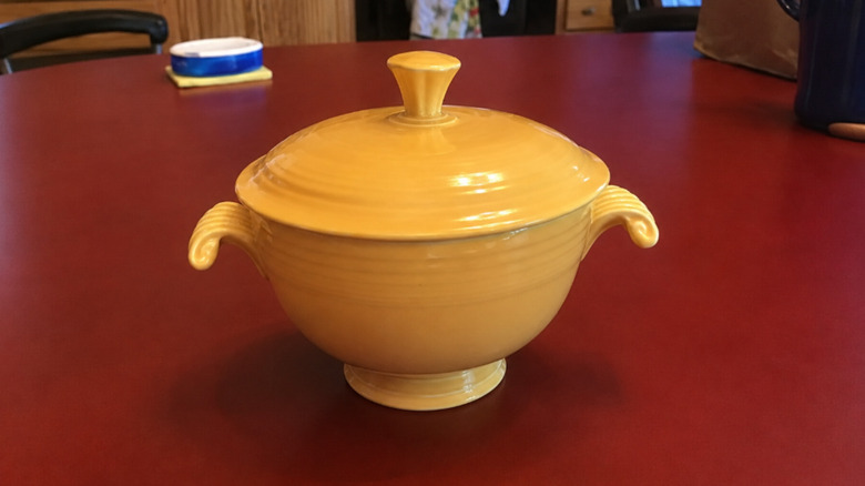 Vintage yellow Fiestaware onion soup bowl with lid witting on a counter