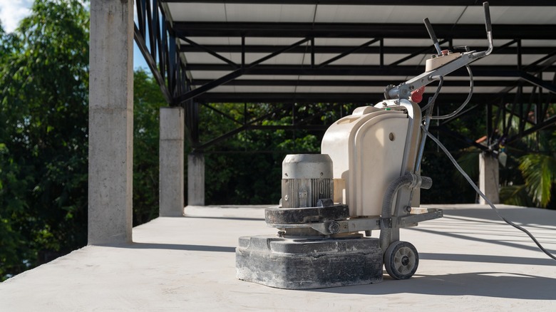 Concrete sanding machine sitting on concrete surface with a roof overhead