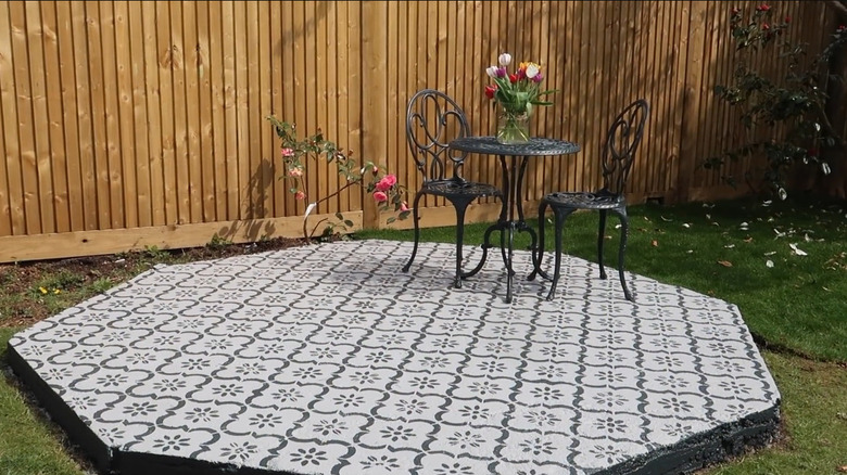 A concrete patio painted with a gray and white faux tile design