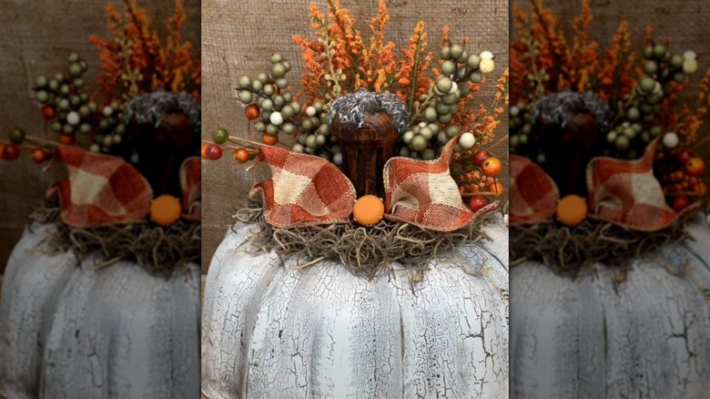 An old bundt cake pan in white with decorative fall items to look like a pumpkin