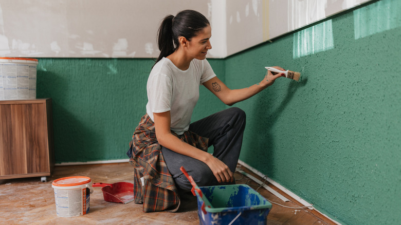 Woman painting a wall using a paintbrush
