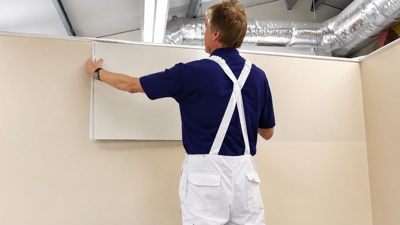 Man on a ladder installing wall liner