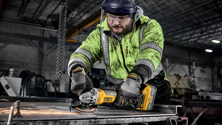 A person in a flurescent jacket steel with a DeWalt angle grinder
