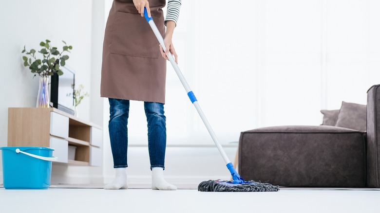 Woman in apron mopping floor