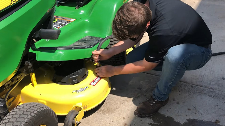 Person connecting a hose to the mower deck wash port