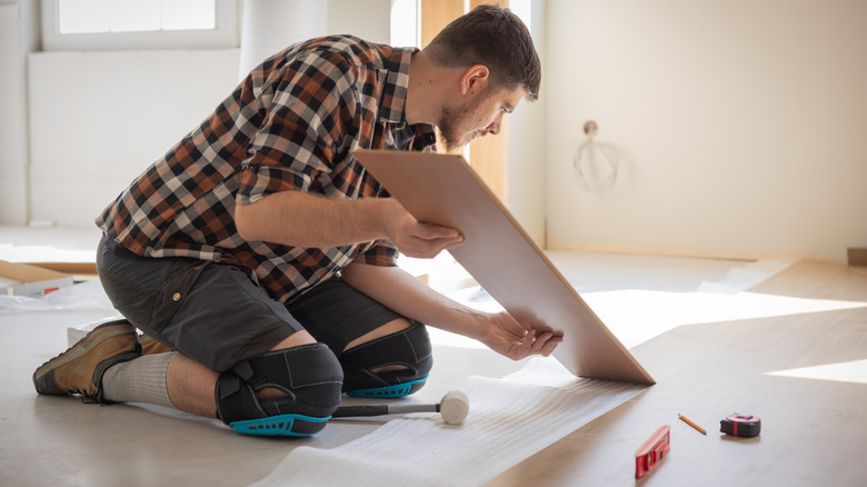 Man installs wood flooring planks