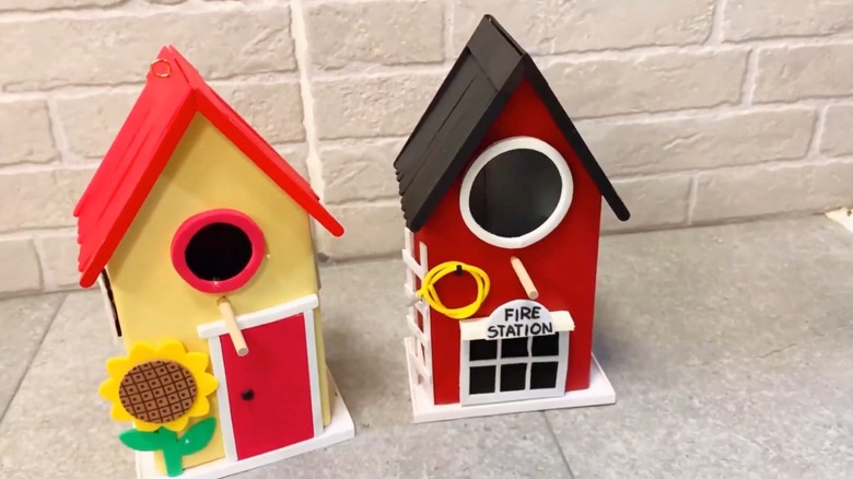 Two pretty birdhouses on a tiled surface