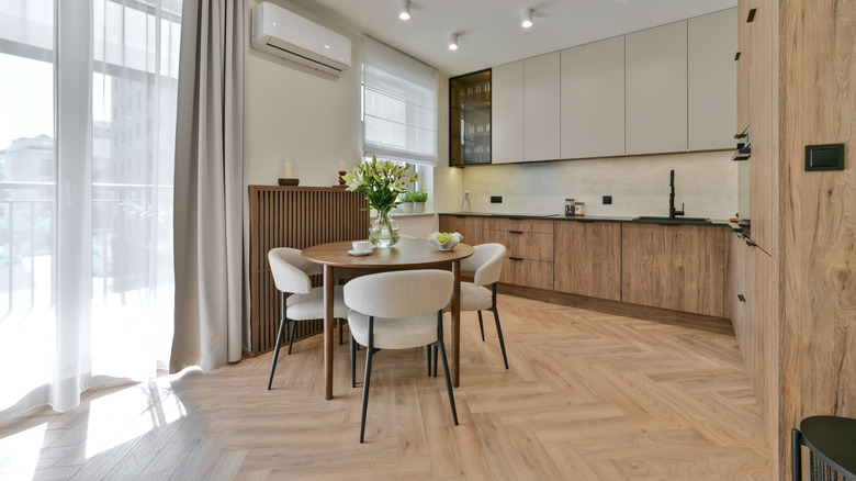 Modern open concept kitchen with light hardwood herringbone style flooring