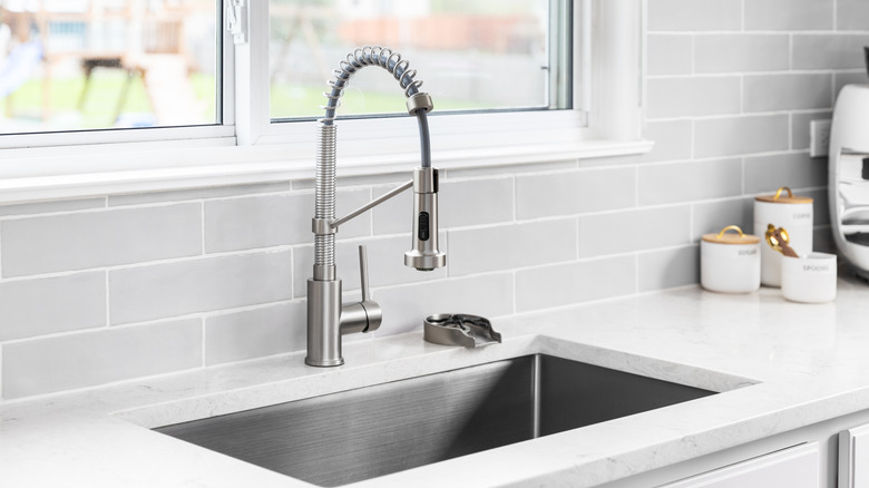 A kitchen sink with a gray subway tile backsplash