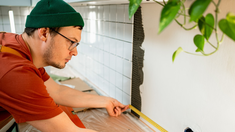 Man installing traditional tile backsplash