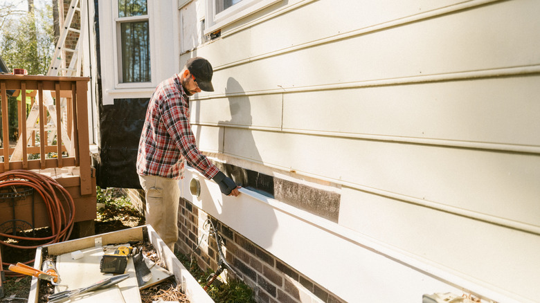 Person replacing panel on side of house