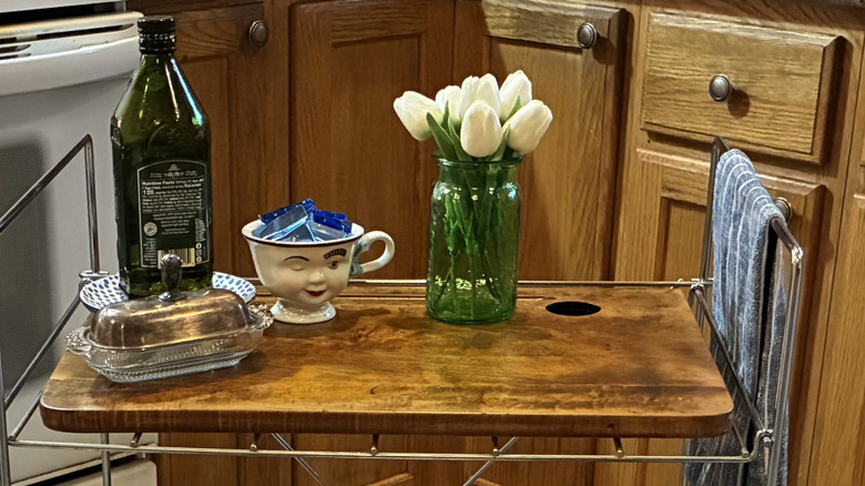 up close of desktop on cart with olive oil, butter dish, teacup of chocolates, flowers in mason jar
