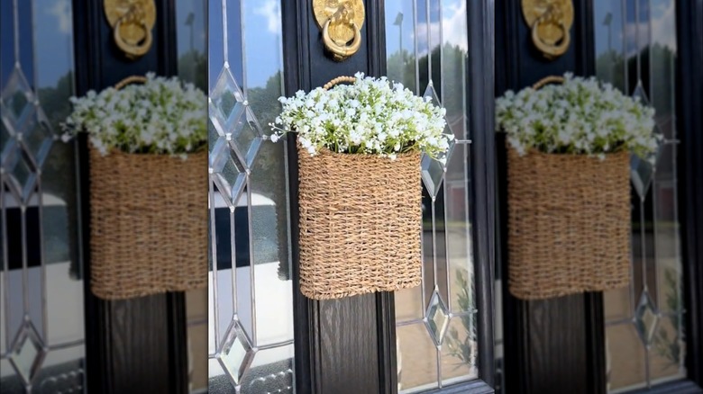 A basket full of flowers hanging on a front door.
