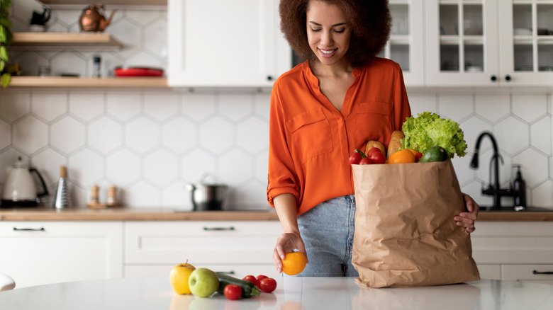 A woman in a modern kitchen unpacking groceries