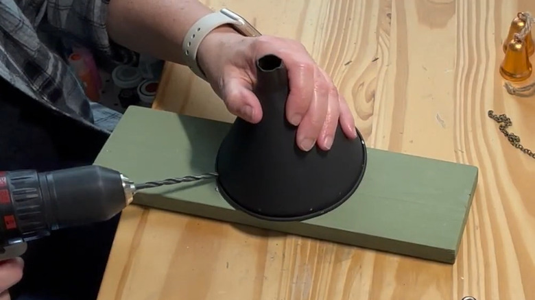 Person drilling holes in a funnel with other craft supplies on the table