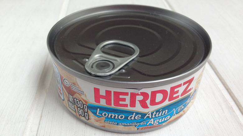 An unopened tuna can on a white surface