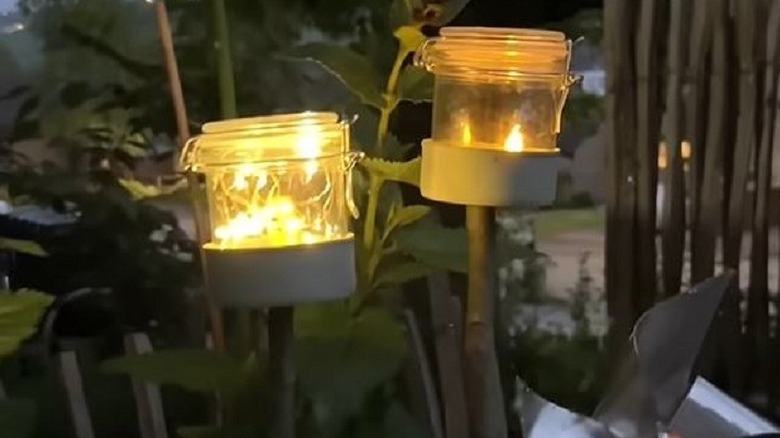 Garden stake lights made from tuna cans and sticks outside in the dark