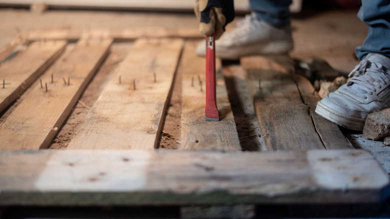 A person disassembling a wood pallet