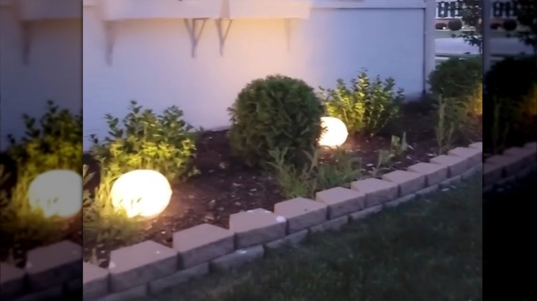 Dark garden space illuminated by Dollar Tree DIY light idea made from punch bowls and solar lights.