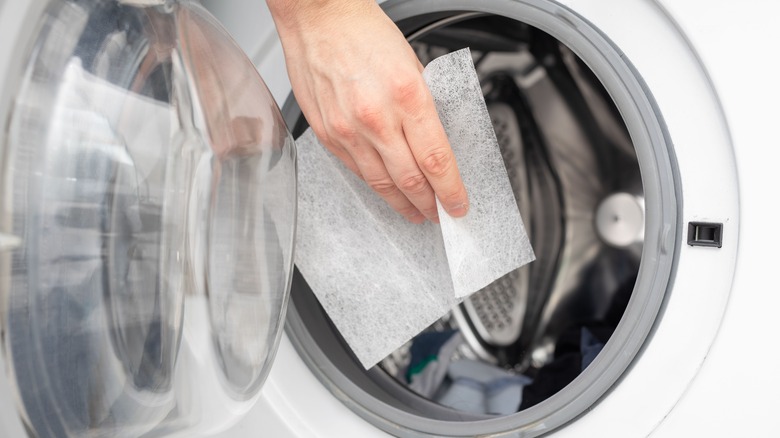 Tossing dryer sheet into washing machine