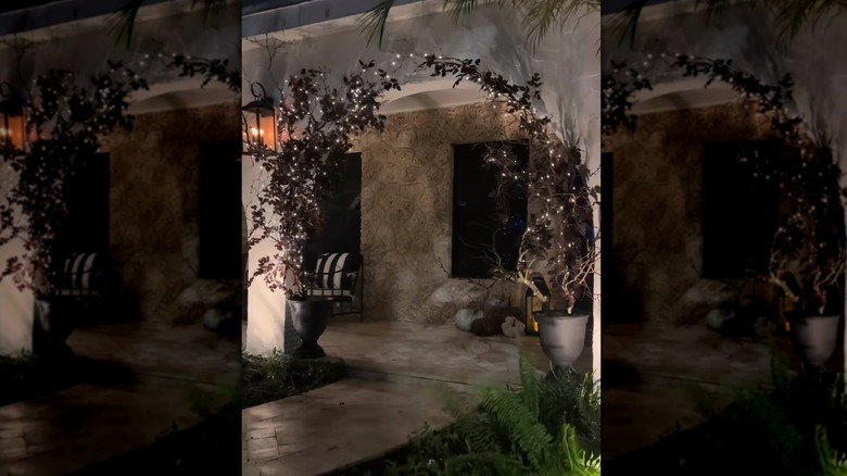 A front porch at night with decorated branches in the archway