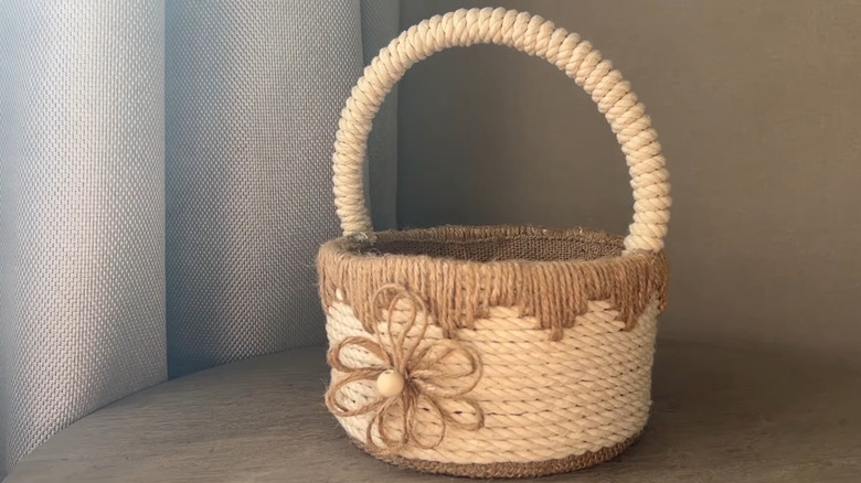 DIY storage basket made from a plastic bucket, rope, and twine