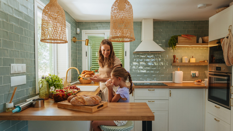 Mother and daughter in the kitchen with a green tile backsplash.