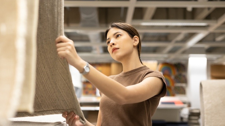 Woman checking rug length while shopping in a store