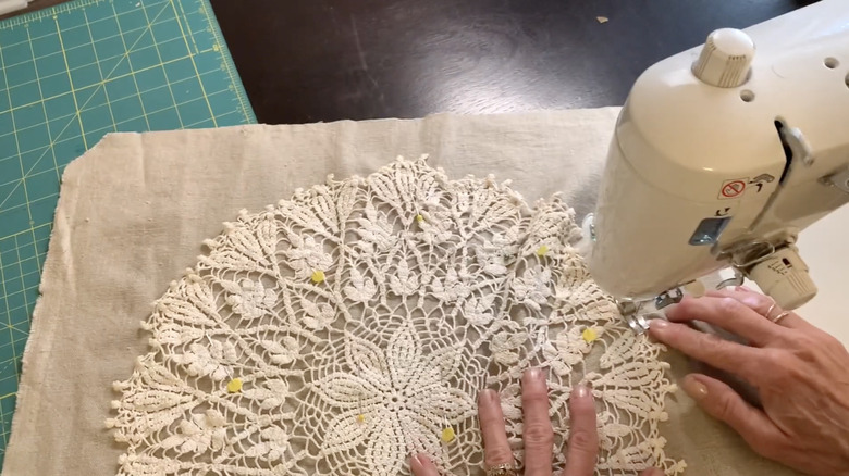hands sewing doily onto fabric